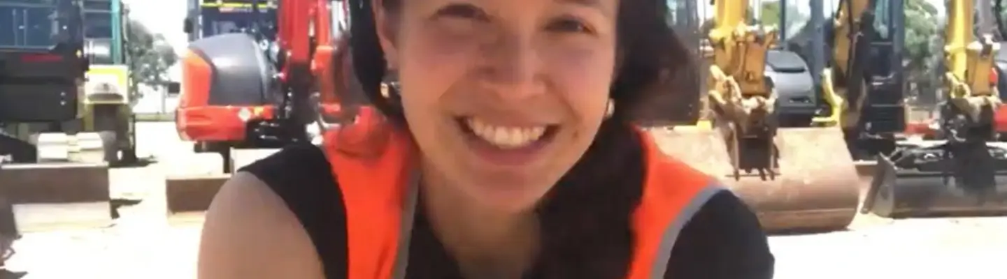 Natasha Haddad in front of excavators at a construction site, highlighting Orange Hire's equipment and team.