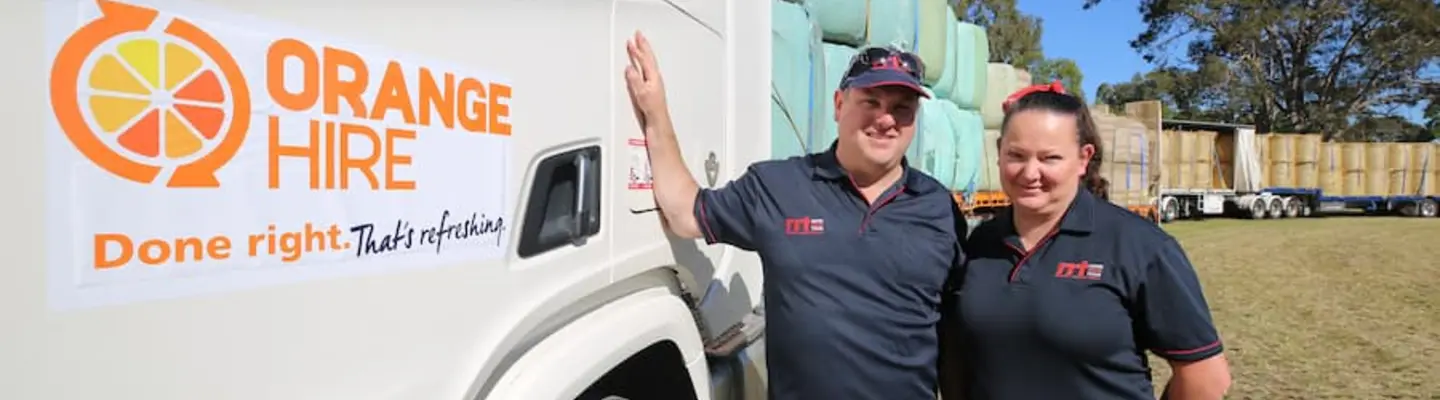 Two uniformed employees standing beside a row of loaded trucks at a worksite, monitoring loading operations and safety.