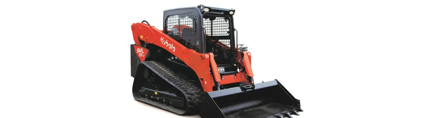Track loader moving materials on a construction site with visible safety barriers and warning signs in place.