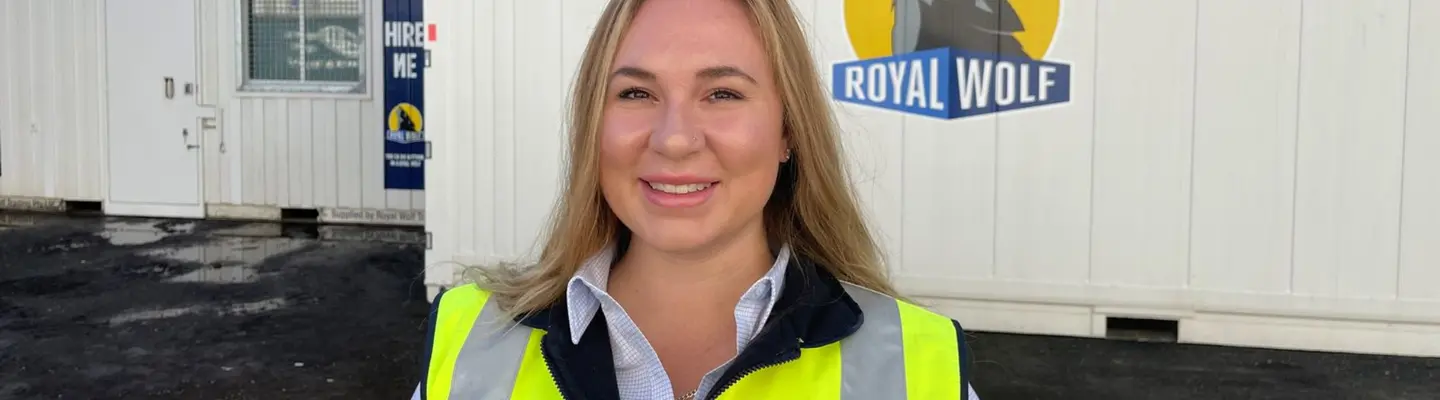 Manager standing in front of shipping containers ready for deployment, used for site storage, offices, or safety equipment housing.