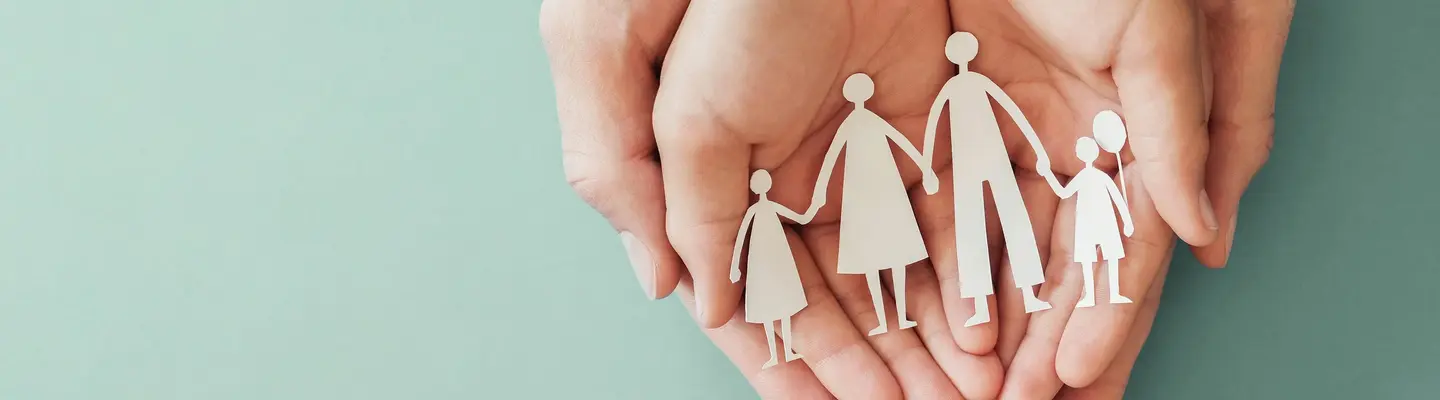 Hands holding a paper cutout of a family symbolizing care and protection.