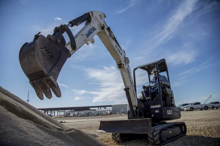 Mini excavator with arm extended near dirt pile