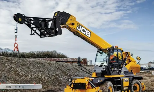 Worker operating machinery at a construction site during safety barrier installation to improve roadside protection.