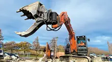 Man operating an excavator on a construction site with safety barriers set up around the work area.