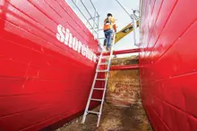  Worker climbing a ladder from an underground trench, with safety barriers and equipment ensuring secure site conditions.