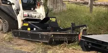 A machine trimming grass in an open field, highlighting land maintenance and safety near construction zones.