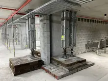 Construction workers installing heavy-duty modular props inside a building for structural support and stability.    