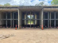 Building supported by steel props placed in central foundation holes to stabilize structure during construction work.