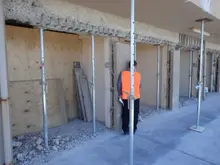 Worker installing temporary supports or props on a construction site to stabilize structures during building work.