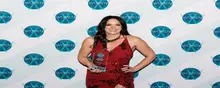 Smiling employee holding an award in front of a company-branded backdrop, recognized for excellence in site safety and barrier services.
