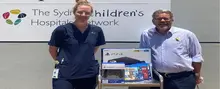 Hospital staff smiling as they unpack new PlayStation consoles donated for children in the pediatric ward.