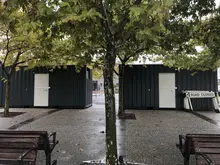 Ticket booth made from a repurposed shipping container, featuring service windows and signage in a compact, functional design.